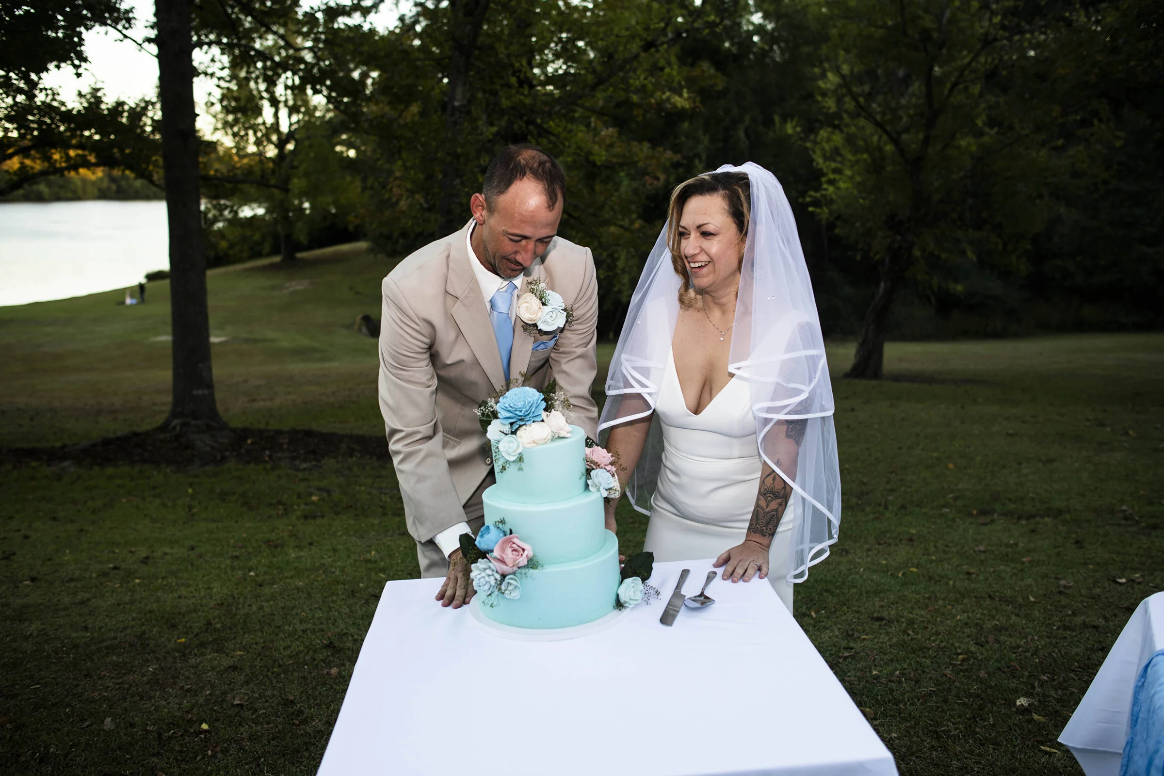 bride and groom cutting light blue wedding cake with blue and white floral accents